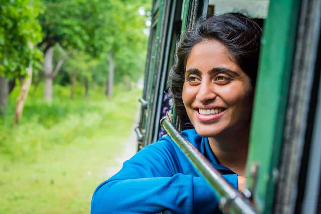 An Indian girl smiles while looking out the window of a vehicle